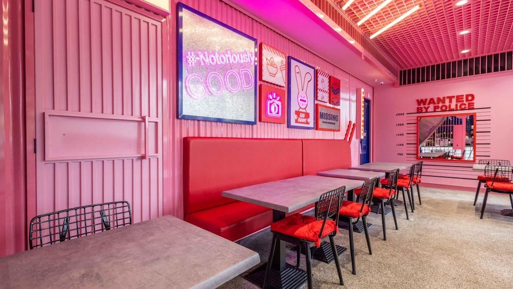 Bright-pink interior decorated with various props. Red booths. (Bad Bunny's interior)