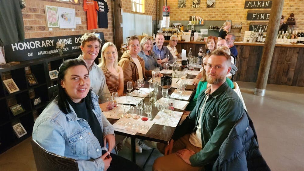 A group of people enjoying wine tasting at a table in a winery's tasting room.