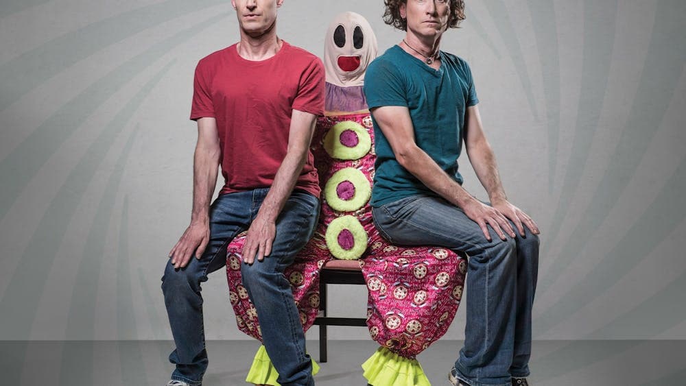 Umbilical Brothers sitting on the lap of a clown called Roadie, looking uncomfortable