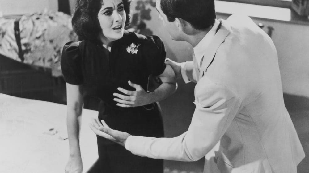 black and white still of woman looking distressed and man speaking to her