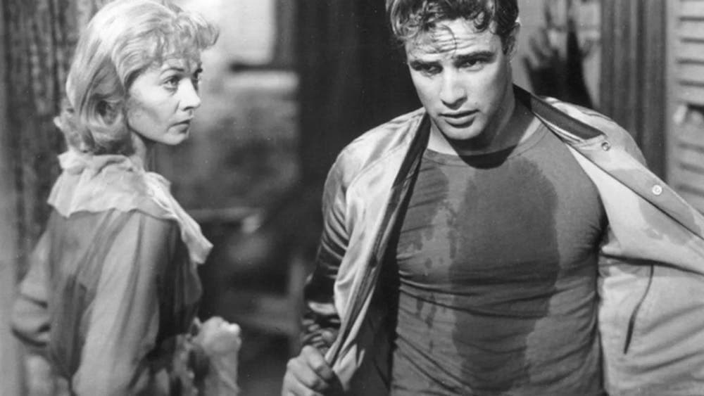 Black and white image of man taking off his jacket walking past woman staring at him