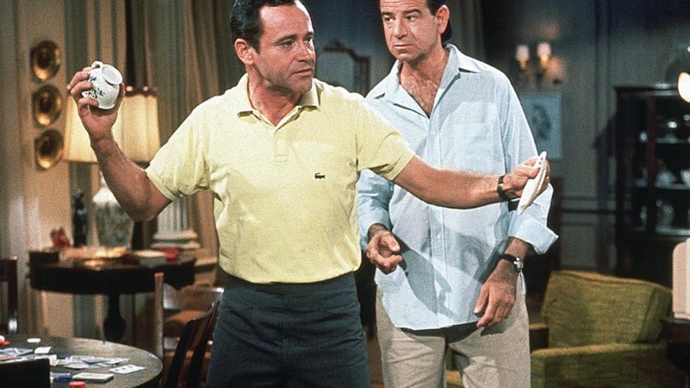 one man holding a baseball and another man wearing a hat backwards