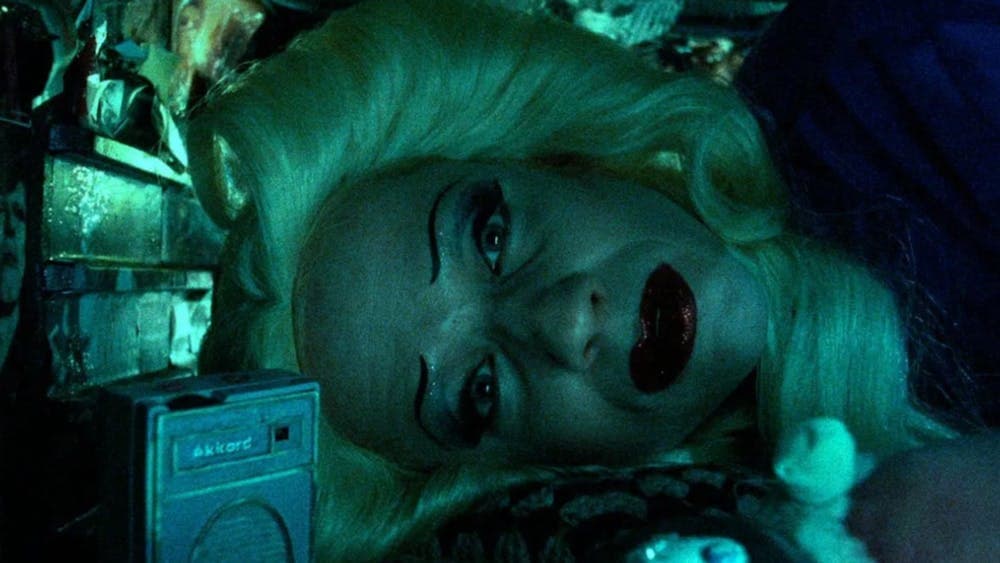 Person tilting head to the side, wearing a wig and vibrant makeup