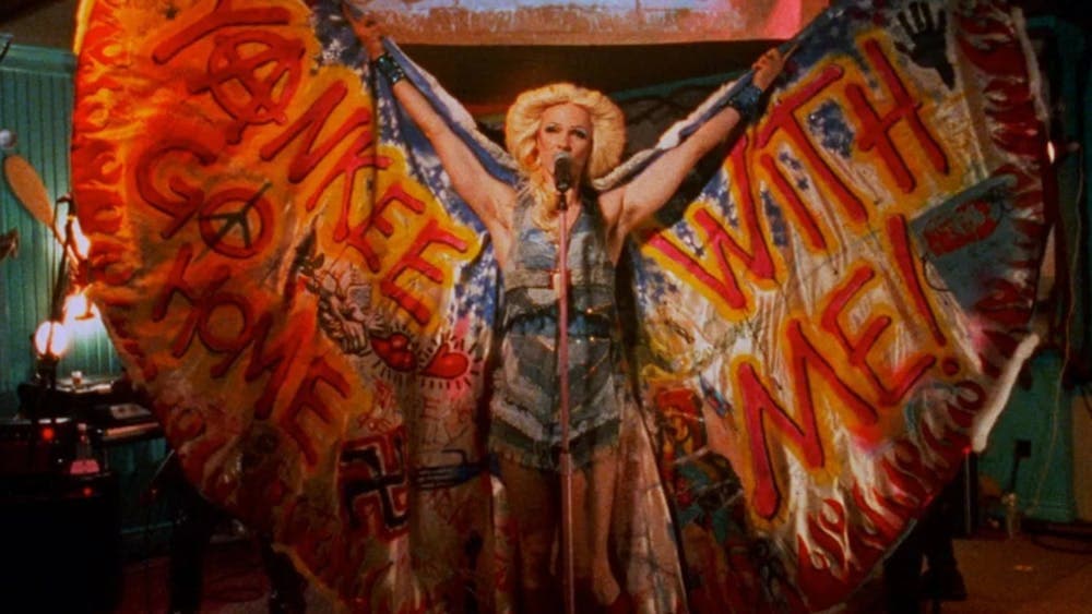 Person performing wearing wings, a wig and vibrant costume