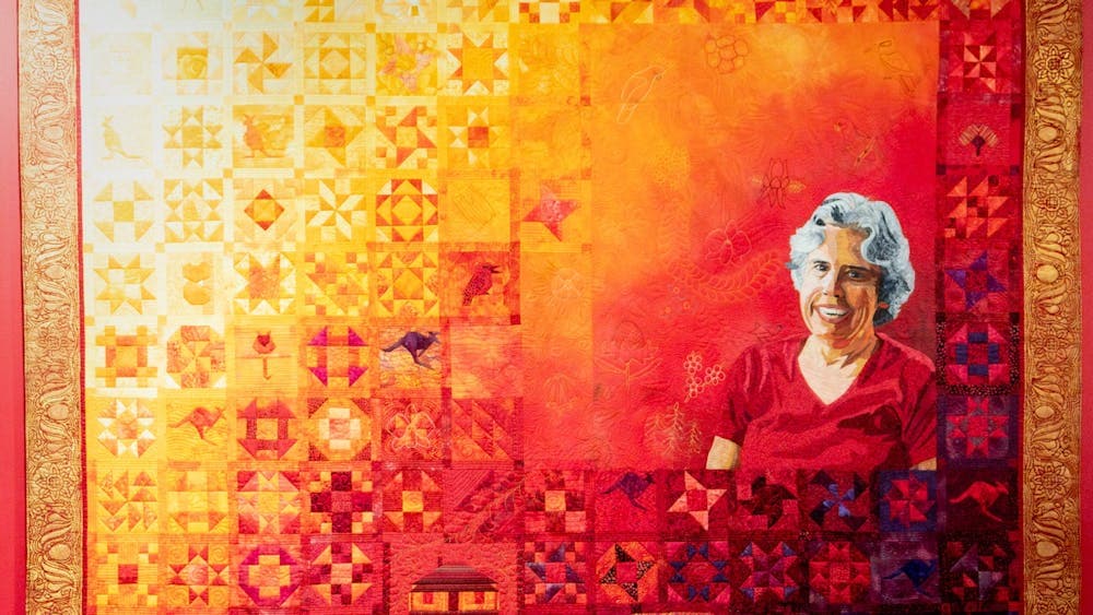 The Quiltmaker quilt by Jenny Bowker depicting Margaret Rolfe in bright yellows, oranges and reds