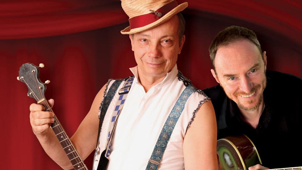 Two men holding string instruments. One man wears a tan top hat.