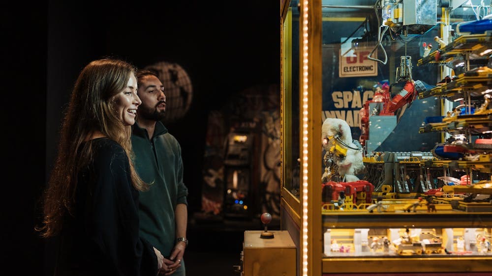 Adult couple enjoying observing a claw machine exhibit in RELICS