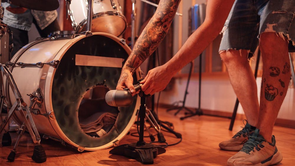 microphone being placed in front of a bass drum of a drum kit